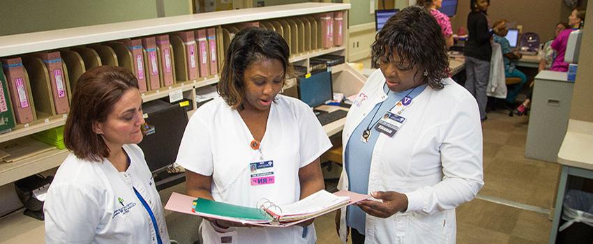 Three nurses in the Bachelors of Science in Nursing (BSN) Program reviewing a chart.