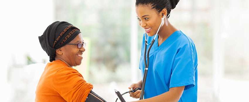 Smiling nurse checking senior patient's blood pressure