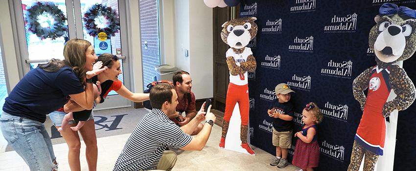 Alumni taking images of their children with cutouts of Southpaw and Ms. Pawla.