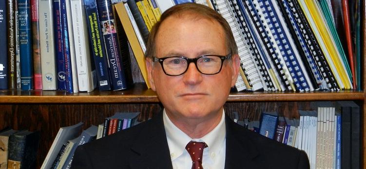 Dr. Michael Daley standing in front of bookcase filled with books